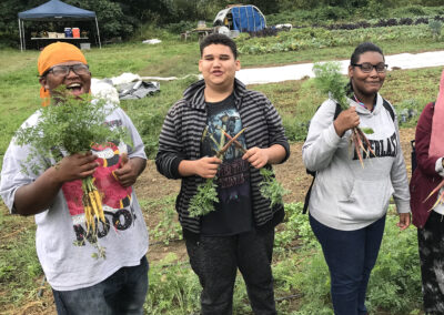 Students on a farm smiling and holding carrots