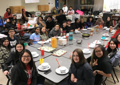 image is of FEEST youtb leaders sitting around a table of food